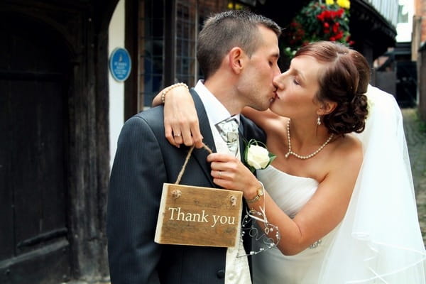 Bride and groom kissing holding thank you sign