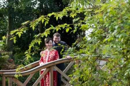 Bride and groom from different cultures standing on bridge