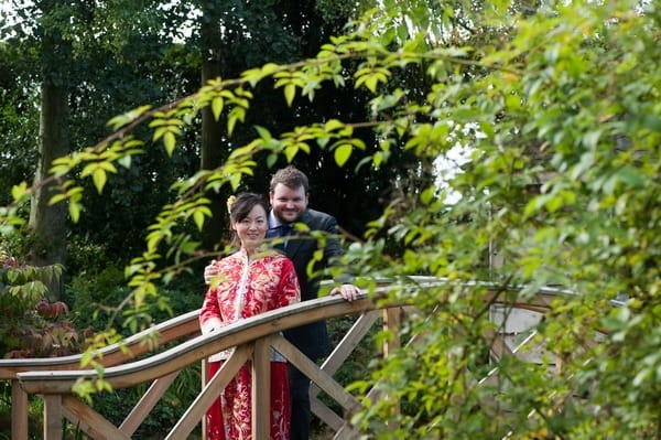Bride and groom from different cultures standing on bridge