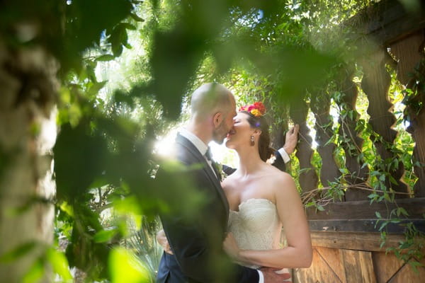 Bride and groom kissing behind branches