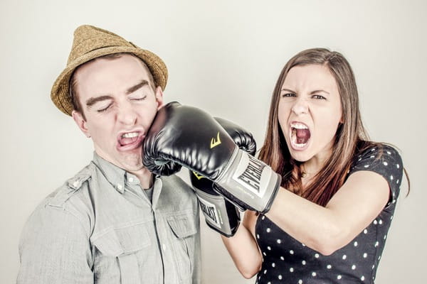 Woman with boxing gloves punching man in face