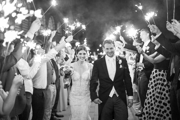 Bride and groom walking past guests holding sparklers