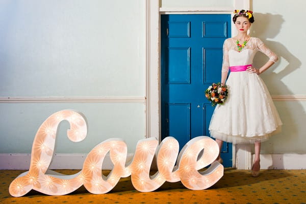 Bride with bouquet standinjg next to love letters