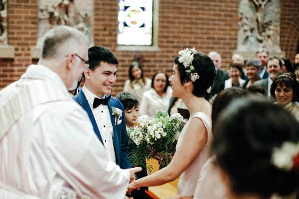 Bride and groom joining hands at altar