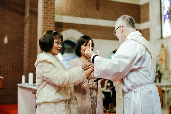 Vicar giving ladies candles at beginning of wedding ceremony