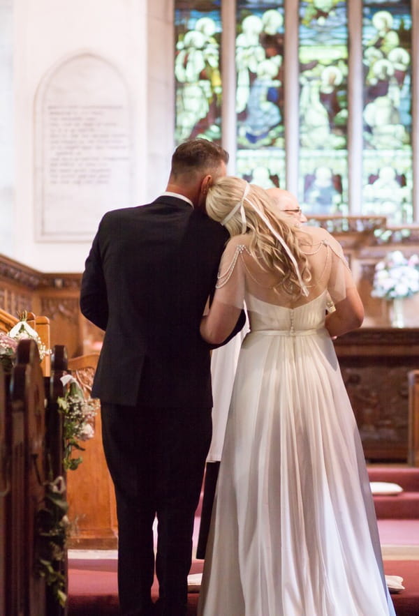 Bride resting head on father's shoulder before he gives her away