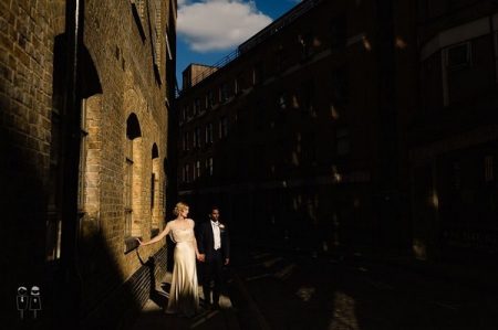 Bride and groom standing between tall buildings - Picture by Paul Joseph Photography