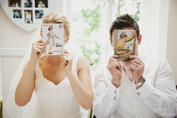 Bride and groom holding husband and wife books in front of their faces - Picture by Gemma Williams Photography