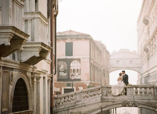 Bride and groom kissing on bridge in Venice