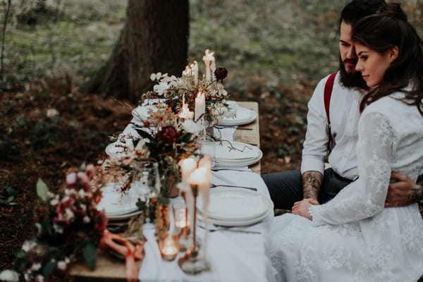 Bride and groom sitting at wedding table in woods