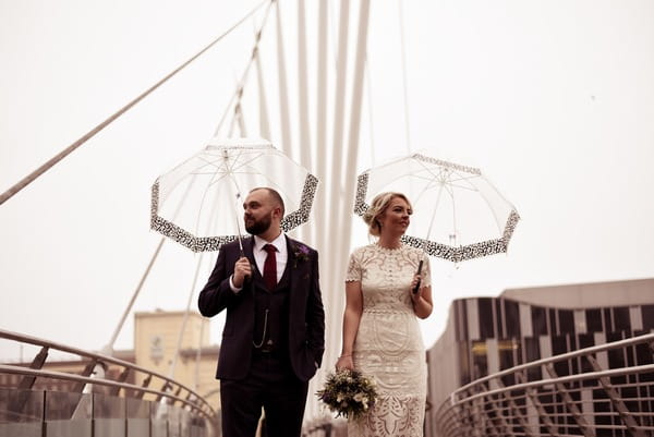 Bride and groom with umbrellas on Manchester Media City Bridge