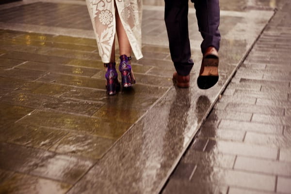 Feet of bride and groom walking on wet pavement