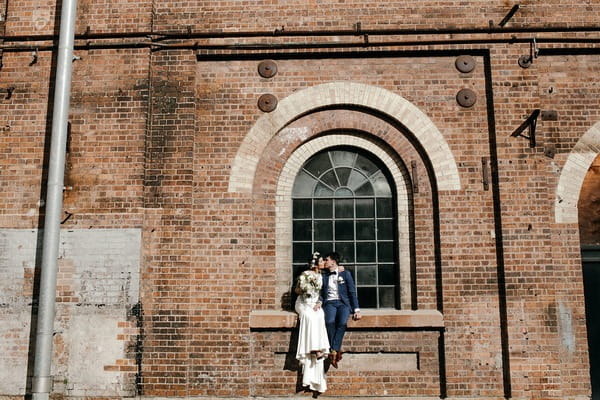 Bride and groom sitting on window ledge