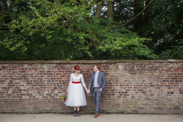 Bride and groom holding hands in front of wall