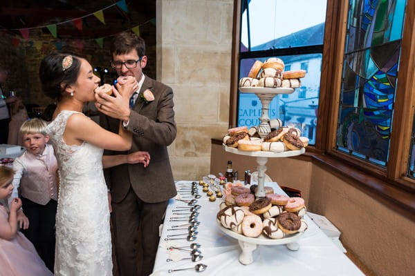 Bride and groom eating doughnuts