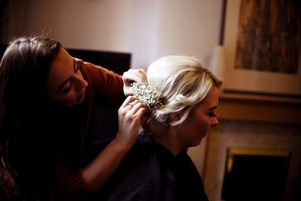 Woman putting accessory in bride's hair