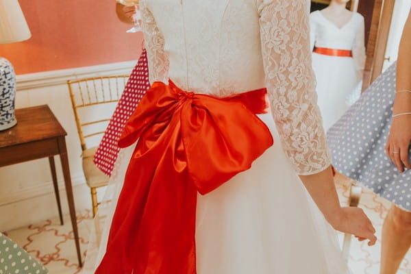 Large red bow on back of bride's wedding dress