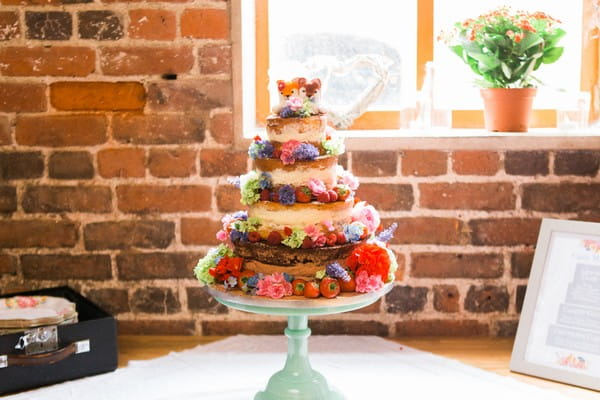 Naked wedding cake with fruit and colourful flowers