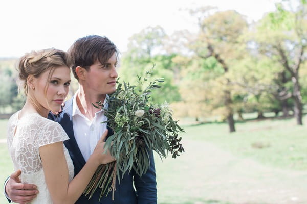 Bride with hand on groom's chest as he looks away