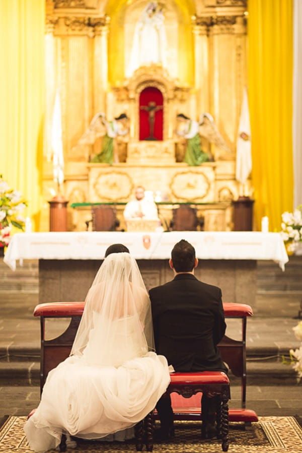 Bride and groom sitting at altar in La Merced church in Guatemala