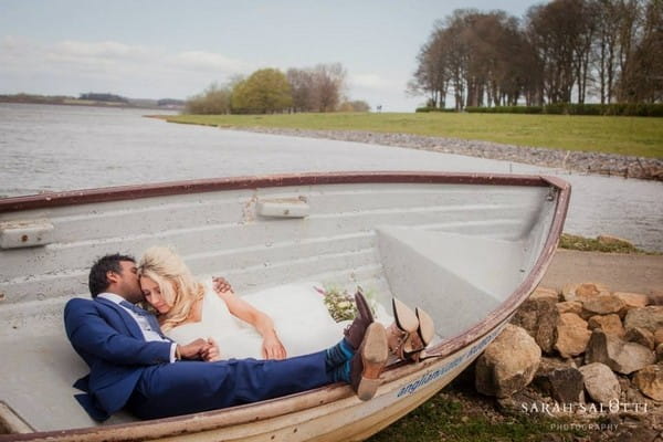 Bride and groom laying down in rowing boat - Picture by Sarah Salotti Photography