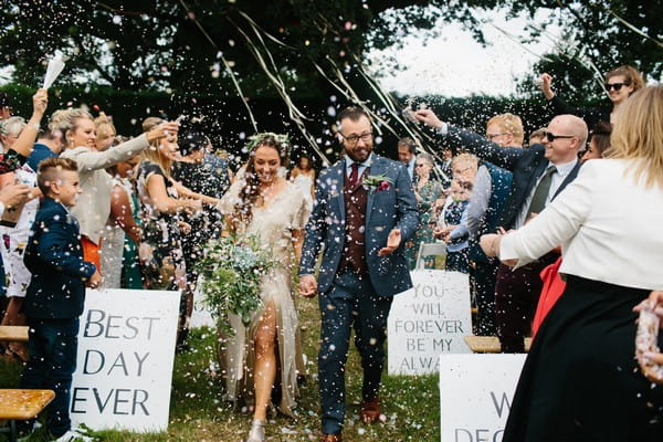 Bride and groom walking through a shower of confetti and streamers - Picture by Dan Hough Photography