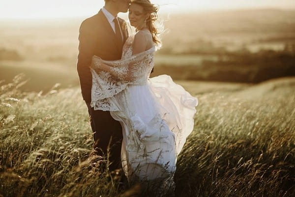 Bride and groom in field in hazy sunshine - Picture by Green Antlers Photography