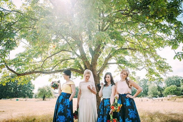 Bride and bridesmaids posing under tree