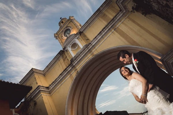 Bride and groom under Santa Catalina Arch and clock tower in Guatemala