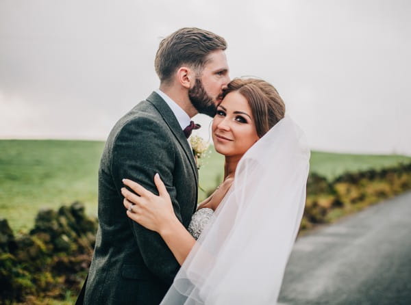 Groom kissing bride on the head