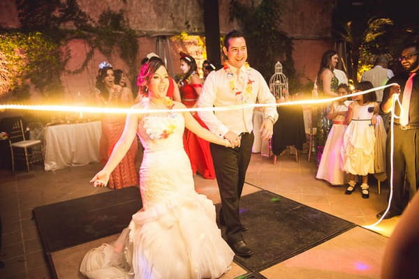 Bride and groom about to limbo dance under light string