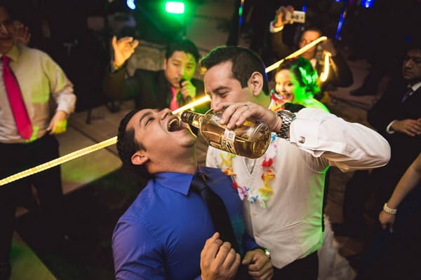 Groom pouring rum into guest's mouth