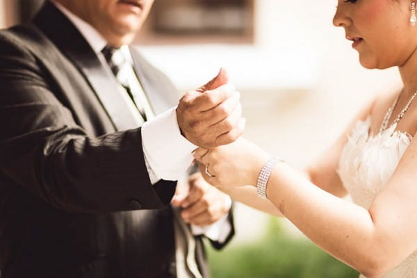 Bride helping father with cufflinks