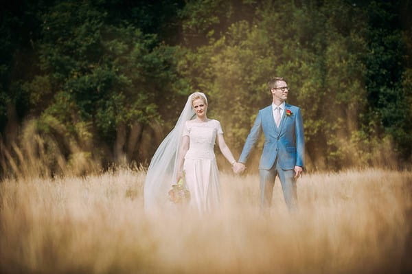 Bride and groom holding hands in a field