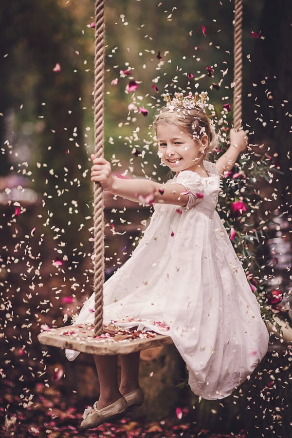 Flower girl on swing as confetti falls around her
