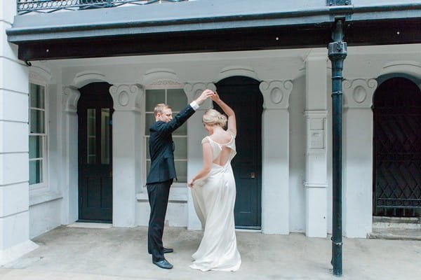 Groom holding bride's arm up as she twirls