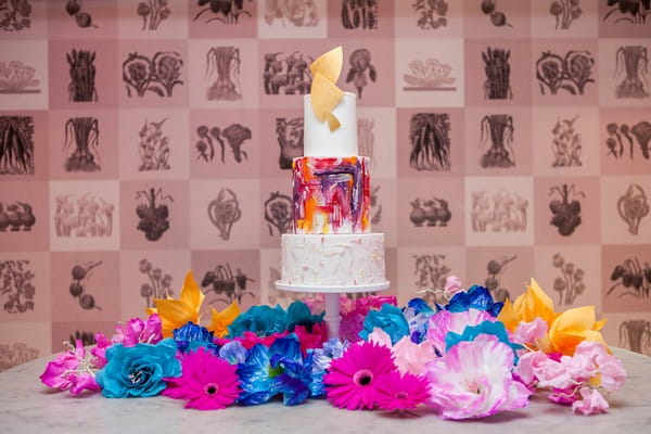 Colourful wedding cake surrounded by brightly coloured flowers