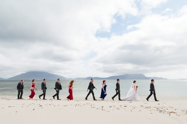 Wedding party walking in a line across beach - Picture by Andy Sidders Photography