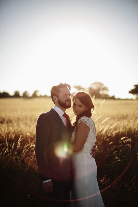 Bride and groom standing in front of wheat field in sunshine - Picture by Paul Fuller Photography