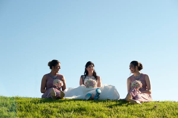 Bride and bridesmaids sitting on grass - Picture by Marina Hannah Photography