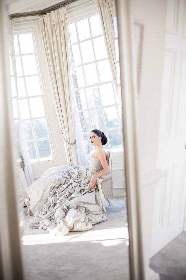 Bride sitting in chair by window at Hedsor House