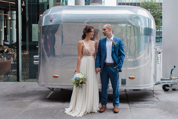 Bride and groom standing in front of metal trailer