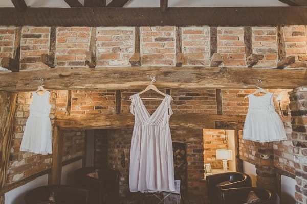 Bridesmaid and flower girl dresses hanging from beam