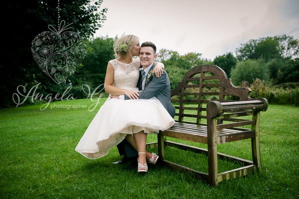 Bride sitting on groom's lap on bench - Picture by Angela G Photographer