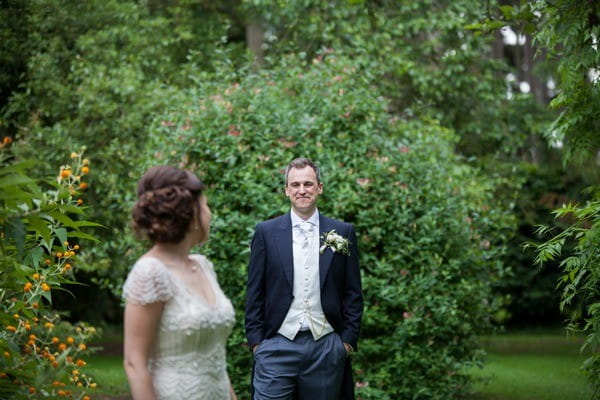 Bride looking over her shoulder at groom wearing white waistcoat and cravat