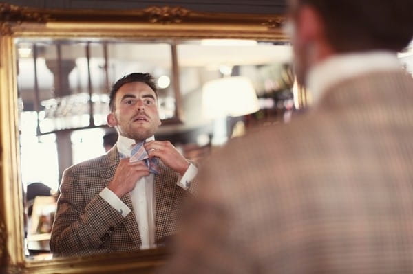 Groom Doing Up Tie in Mirror