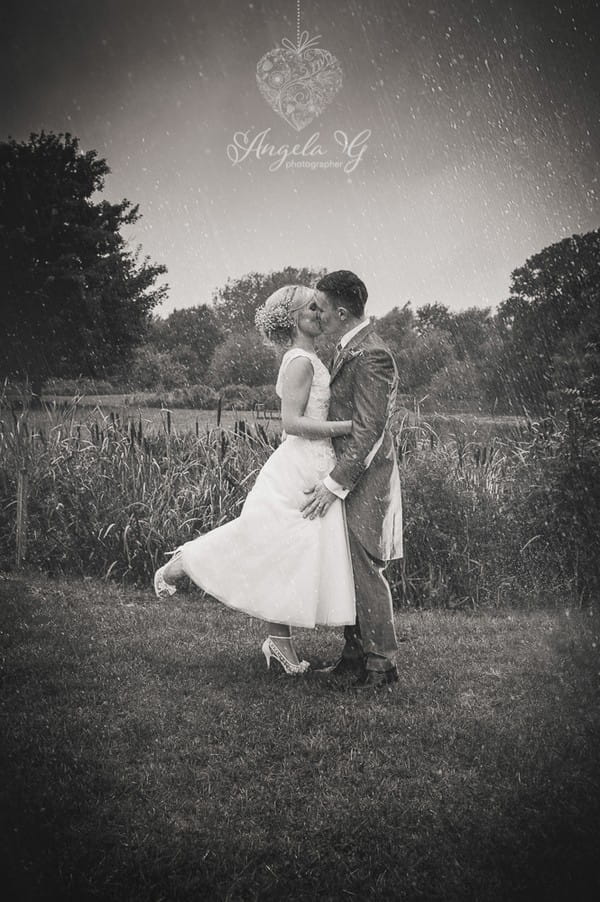 Bride and groom kissing in rain - Picture by Angela G Photographer