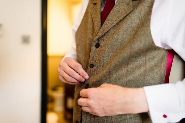 Groom Doing Up Buttons on Tweed Red Check Waistcoat