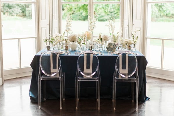 Wedding table with navy blue tablecloth and ghost chairs