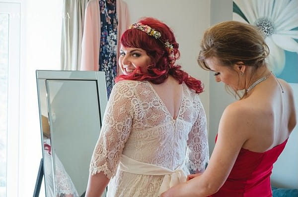 Bride looking over shoulder as dress is done up